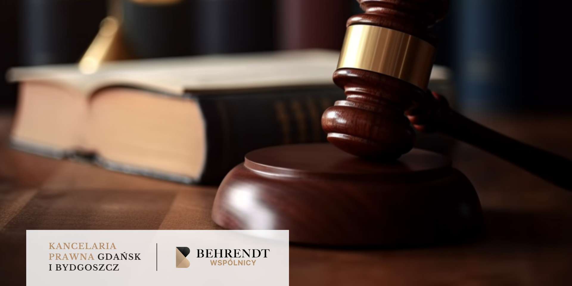 Młotek sędziowski leży na podstawce na biurku, w tle stoi otwarta książka prawnicza