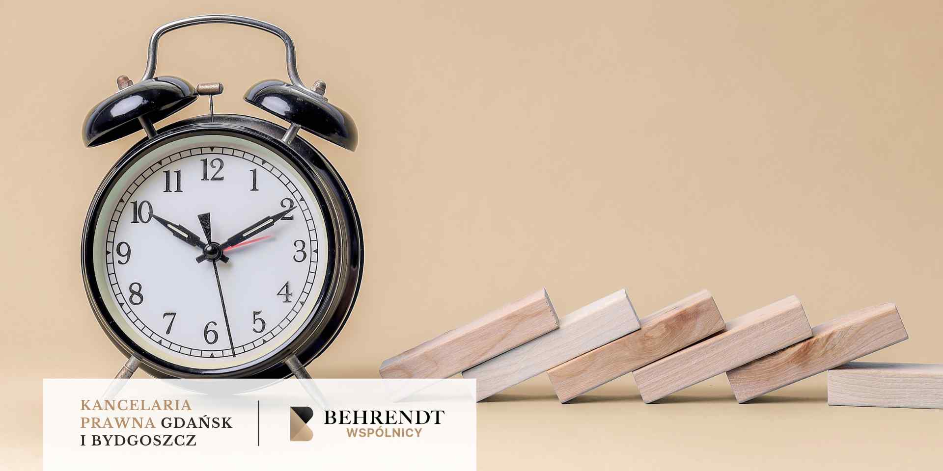 
Na beżowym tle stoi duży, czarny budzik, a obok niego ułożone są drewniane klocki w rzędzie, symbolizujące upływ czasu i efekt domina