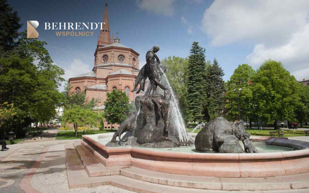 Widok na plac w Bydgoszczy z pomnikiem Potop - fontanną z figurą mężczyzny i zwierząt, na tle ceglanego, neogotyckiego kościoła