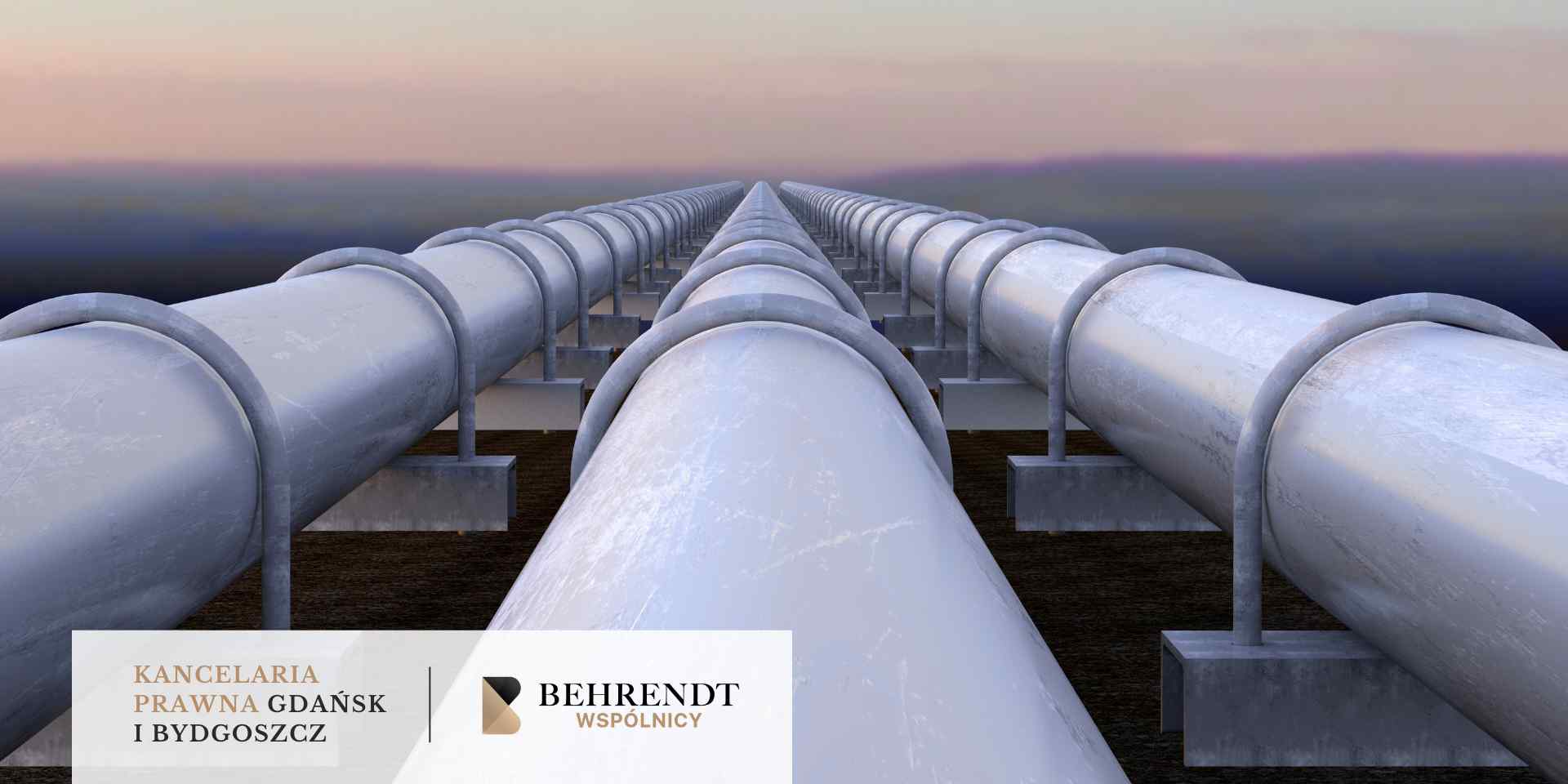 Długi gazociąg na wysokich podporach biegnie nad gęstymi drzewami oświetlonymi zachodzącym słońcem