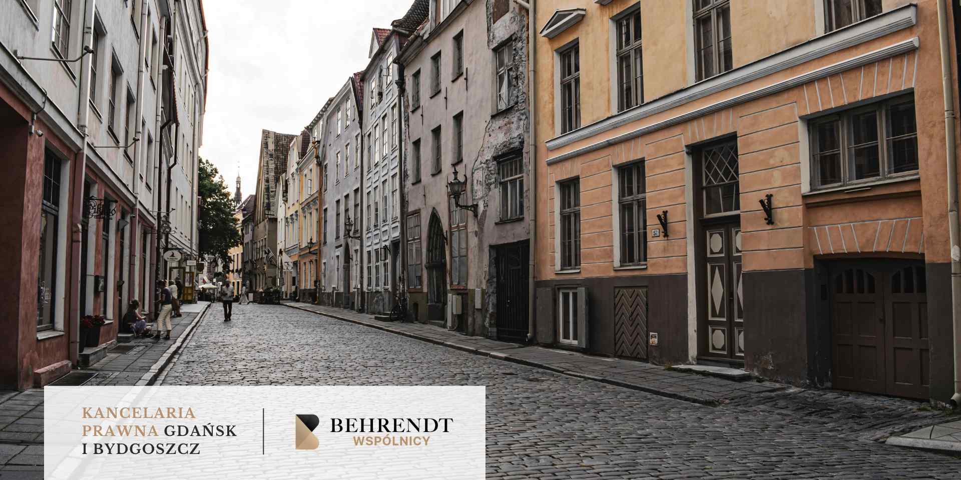 Wąska, brukowana ulica w europejskim mieście, otoczona zabytkowymi, kamienicami o różnokolorowych fasadach.