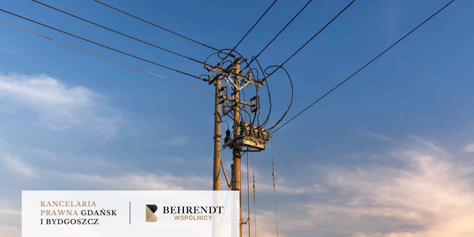 Betonowy słup energetyczny z rozbudowaną siecią przewodów i izolatorów stoi na tle błękitnego nieba.