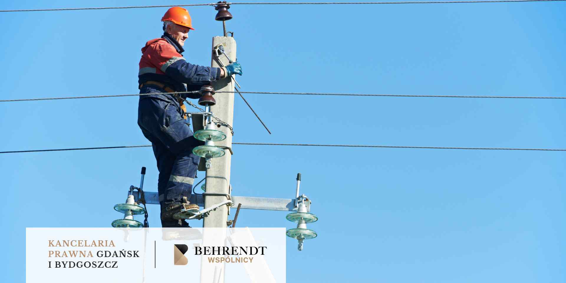 Technik w pomarańczowym kasku i odzieży ochronnej wykonuje prace serwisowe na słupie energetycznym pod bezchmurnym niebem.