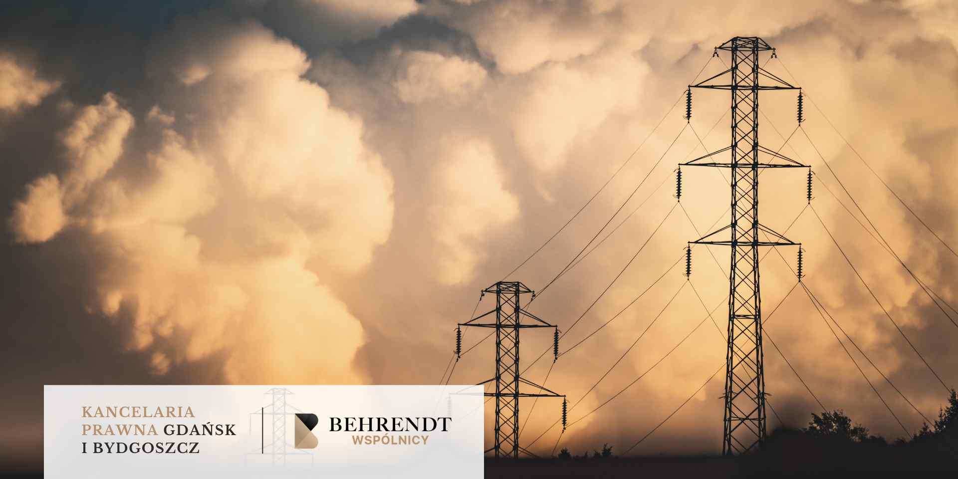 Dwa wysokie słupy energetyczne z przewodami górują nad okolicą na tle dynamicznych, pomarańczowo-brązowych chmur podczas zachodu słońca.