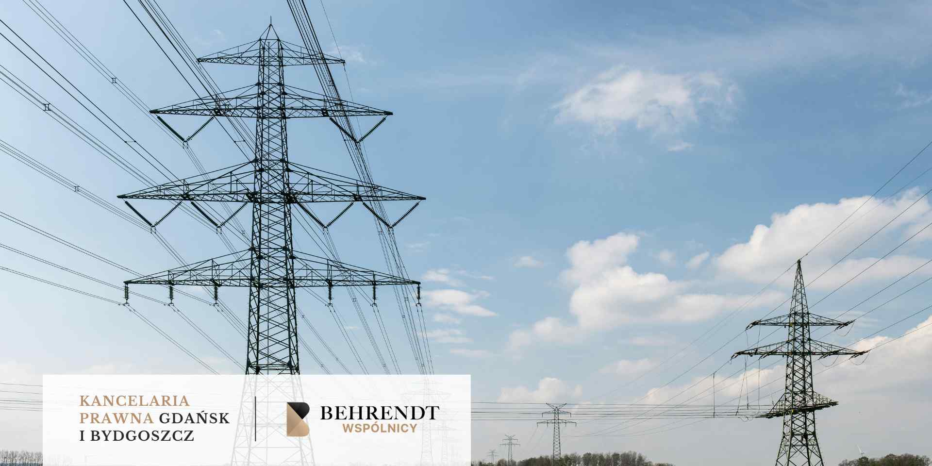 Wysokie metalowe słupy wysokiego napięcia z gęstą siecią przewodów elektrycznych na tle jasnoniebieskiego nieba z lekkimi chmurami.