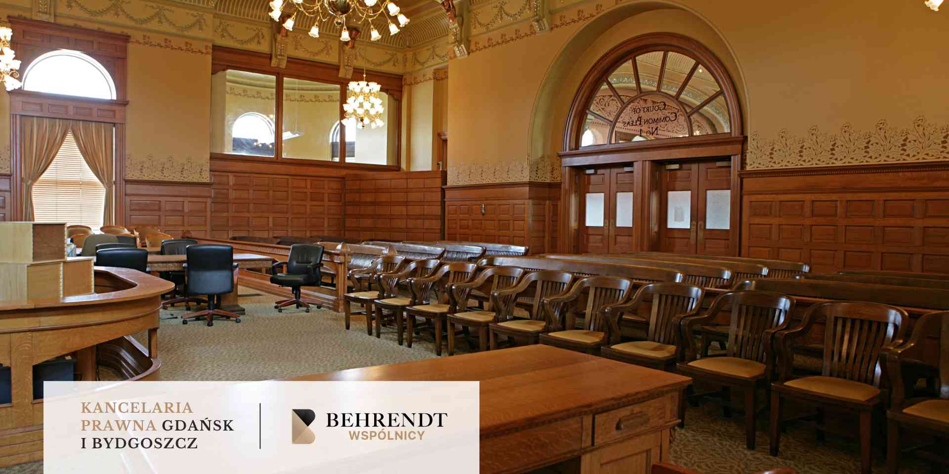 Pusta, zabytkowa sala rozpraw z drewnianymi ławami – miejsce prowadzenia procesów karnych.