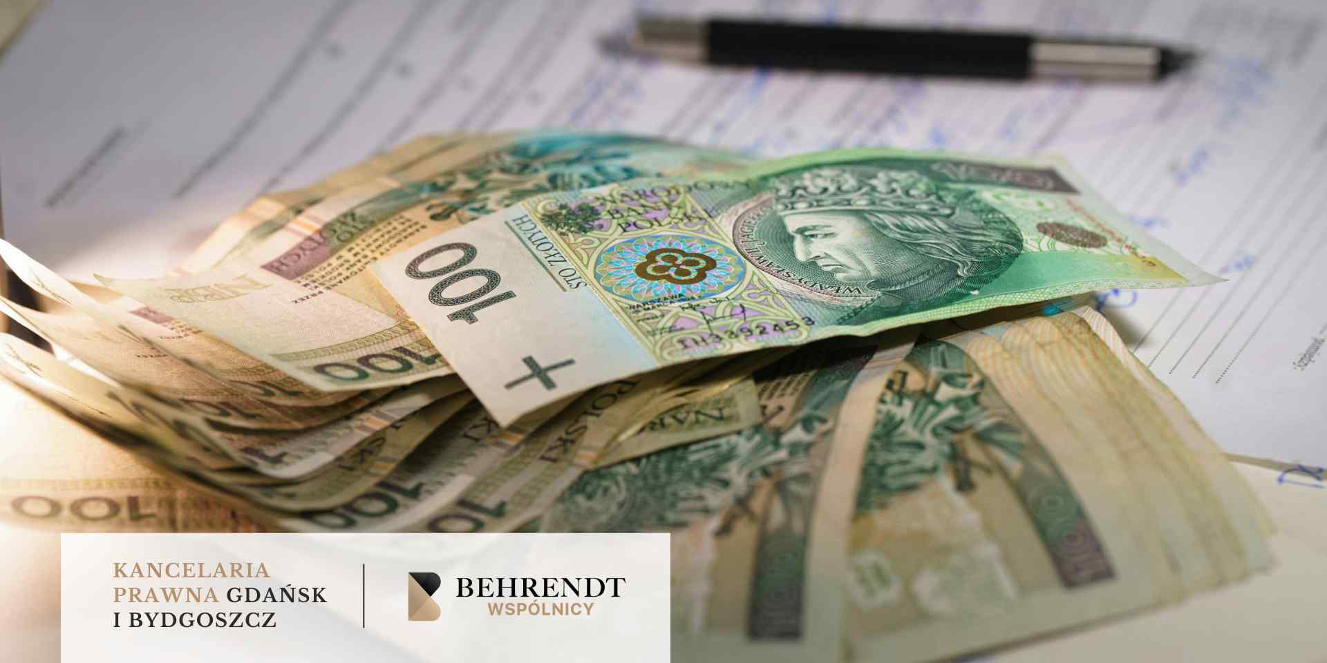 Plik banknotów o nominale 100 złotych polskich (PLN) leżący na wypełnionych dokumentach i formularzach; w tle widoczny jest czarny długopis.