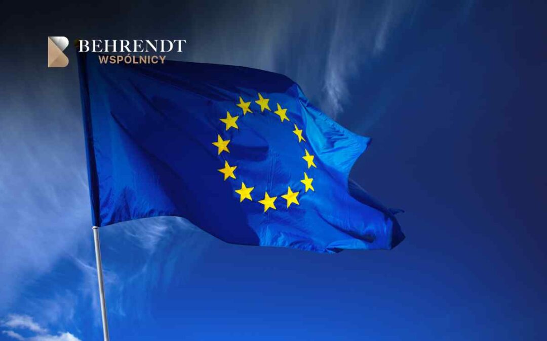 Flaga Unii Europejskiej powiewająca na tle błękitnego nieba z lekkimi chmurami.