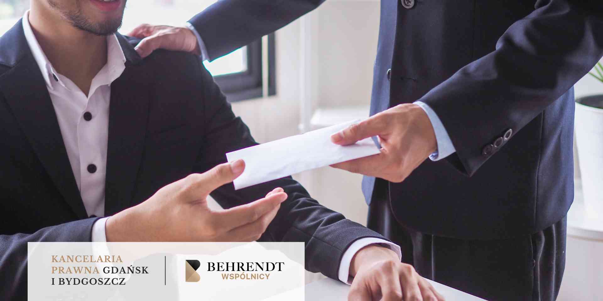 Mężczyzna w ciemnej marynarce przekazuje białą kopertę drugiej osobie, trzymając jednocześnie dłoń na jej ramieniu w geście wsparcia.
