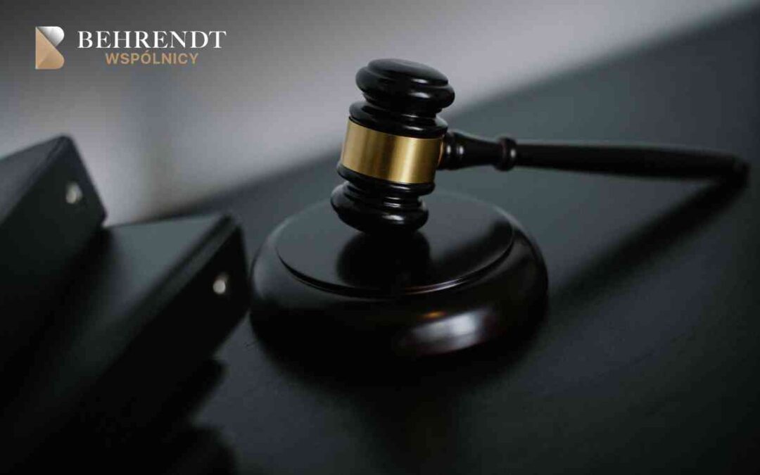 Judge's gavel resting on a dark polished desk with the Behrendt WSPÓLNICY logo in the upper-left corner, conveying legal context.