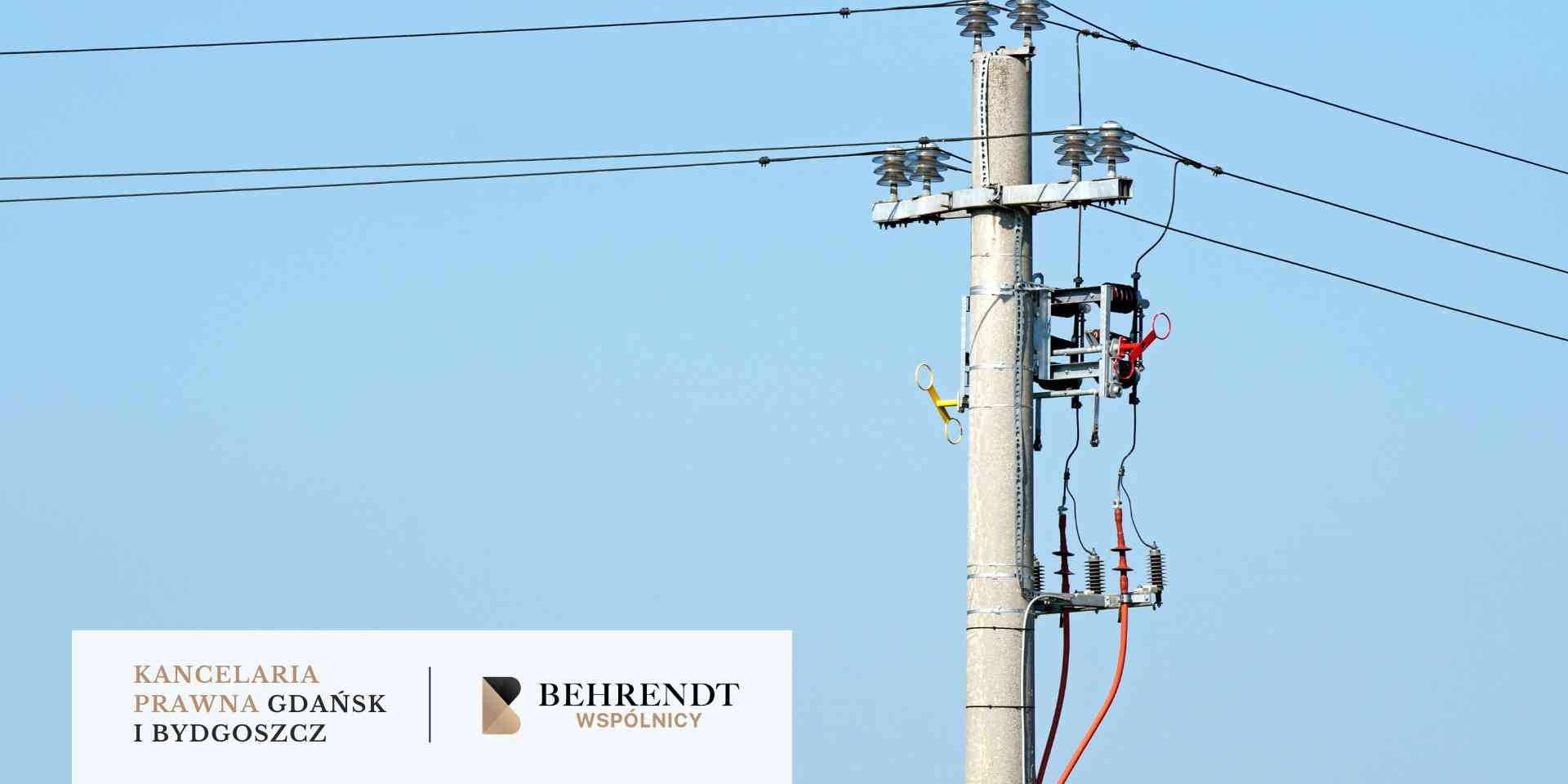 Szereg stalowych słupów energetycznych i liczne linie wysokiego napięcia ciągnące się nad horyzontem w stronę zachodzącego słońca; niebo w odcieniach złota i błękitu.