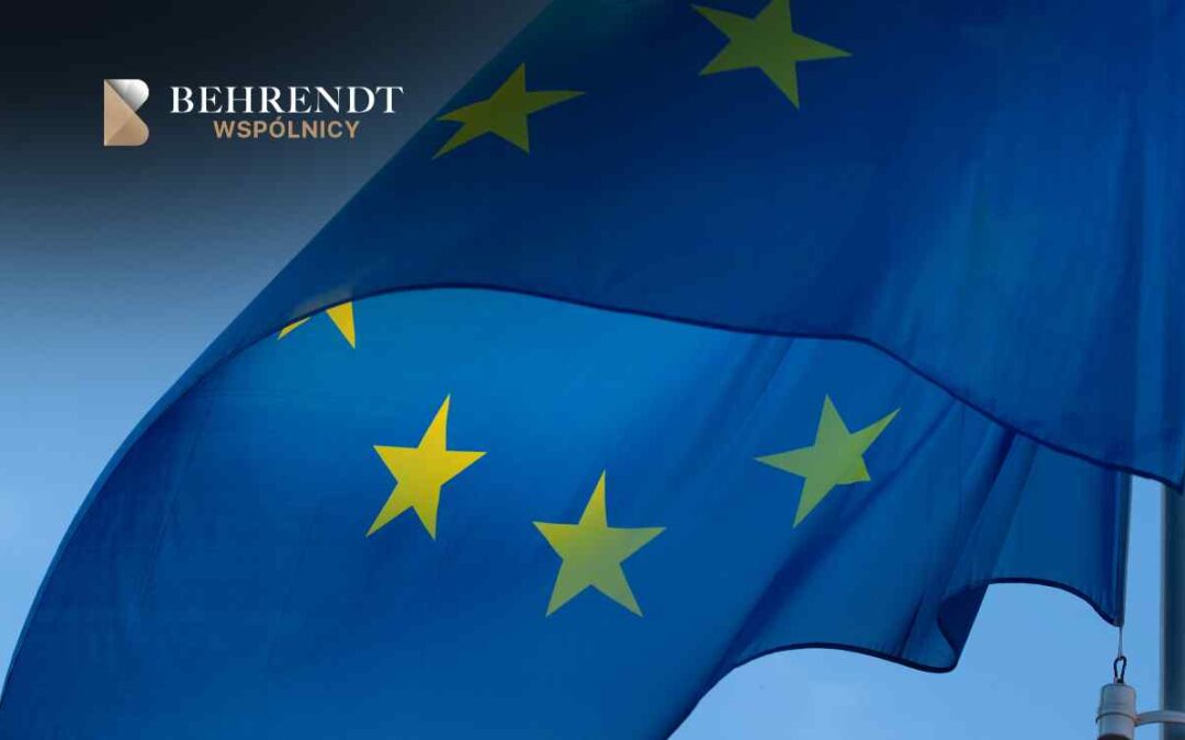 Close-up of a blue European Union flag with yellow stars, featuring the Behrendt Wspólnicy logo in the top-left corner.