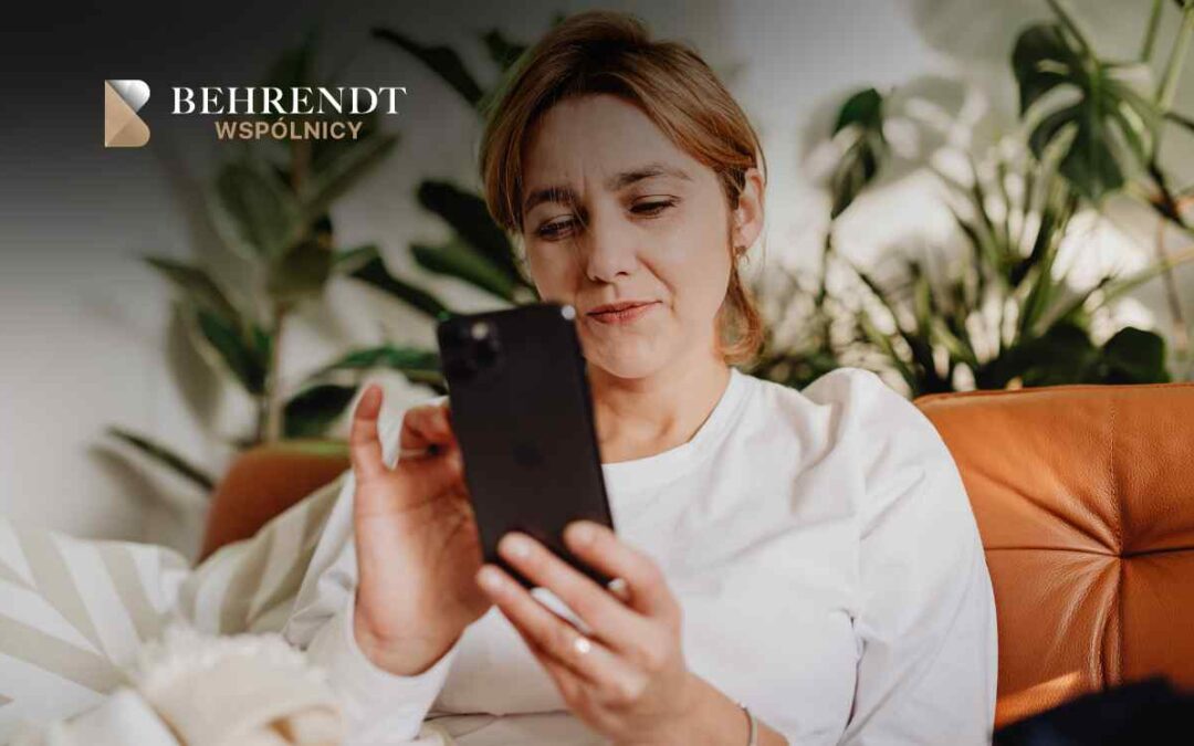 Woman in a white shirt sits on a tan couch, looking at a smartphone; Behrendt Wspólnicy logo in the top-left corner.
