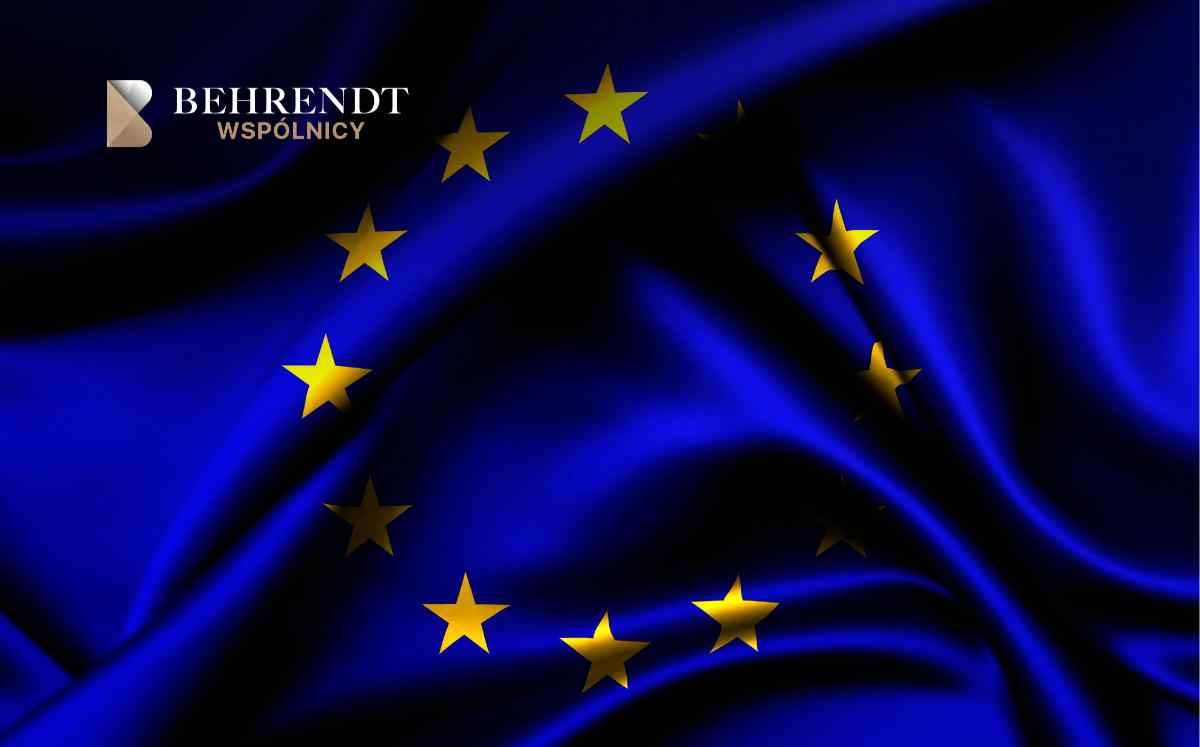 European Union flag with gold stars on blue fabric, and the Behrendt Wspólnicy logo in the top-left corner.