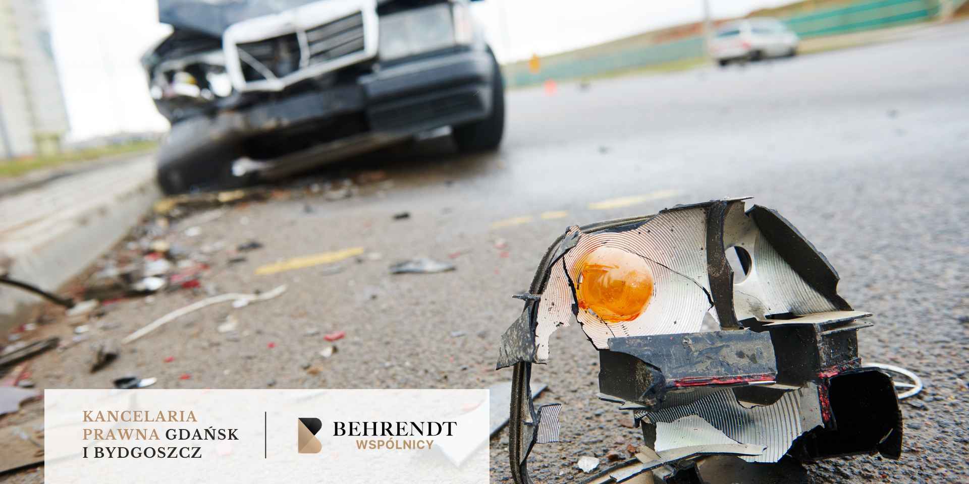 Rozbity reflektor samochodowy na asfalcie i uszkodzone auto w tle – logo Kancelarii Prawnej Behrendt i Wspólnicy
