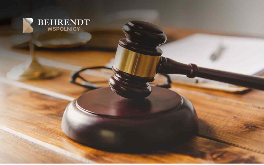 Gavel on a wooden desk with the Behrendt Wspólnicy logo in the top left corner, suggesting a legal setting.