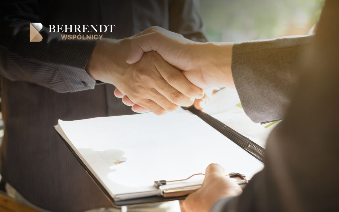 Two people shake hands over a clipboard with a document, symbolizing a business agreement or partnership, logo visible in the corner.