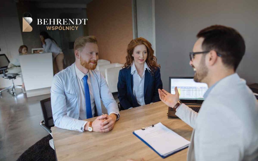Three professionals in a modern office discuss at a conference table; Behrendt Wspólnicy logo in the top-left. **Note:** The logo text is included if relevant to context.