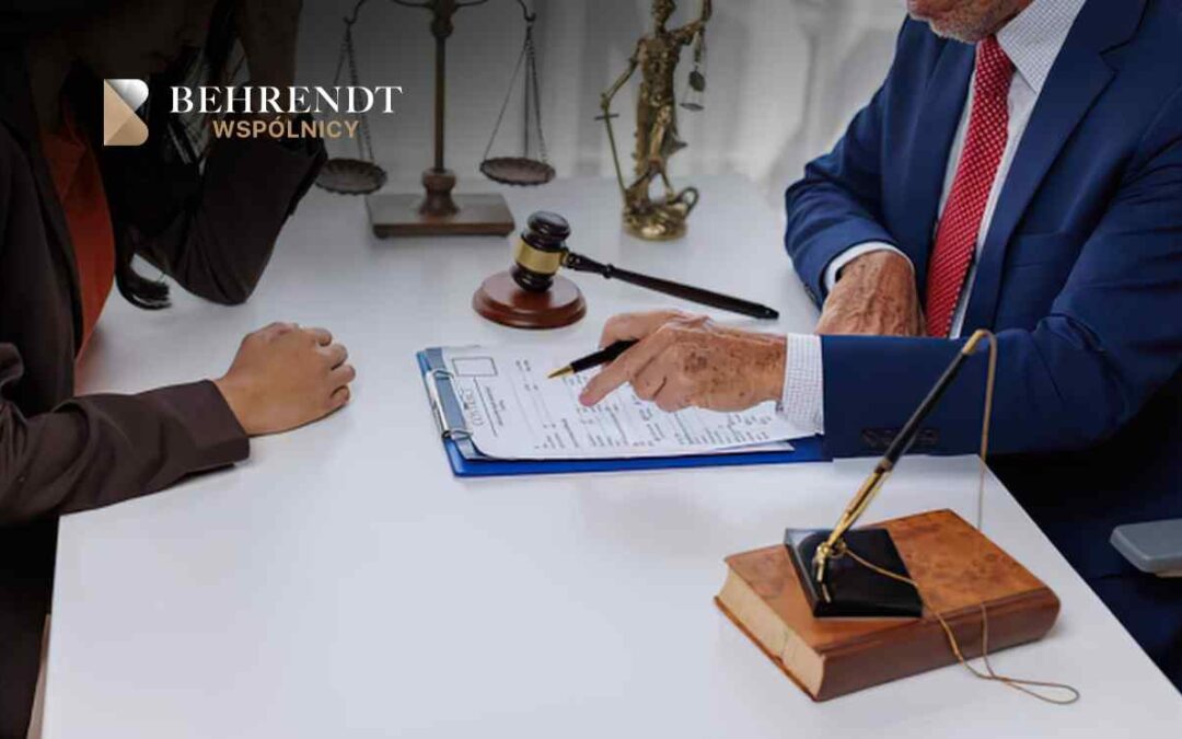 Lawyer in a blue suit signs a document for a client across a white desk, with a gavel, scales of justice, and legal books visible nearby.