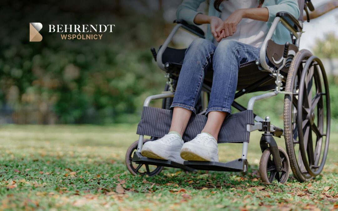 Person in a wheelchair outdoors on a grassy park area with a Behrendt Wspólnicy logo in the top-left corner.] 2]