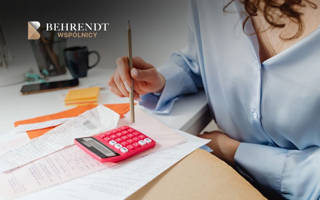 Person at a desk using a pencil on receipts with a pink calculator; Behrendt Wspólnicy logo in the top-left.