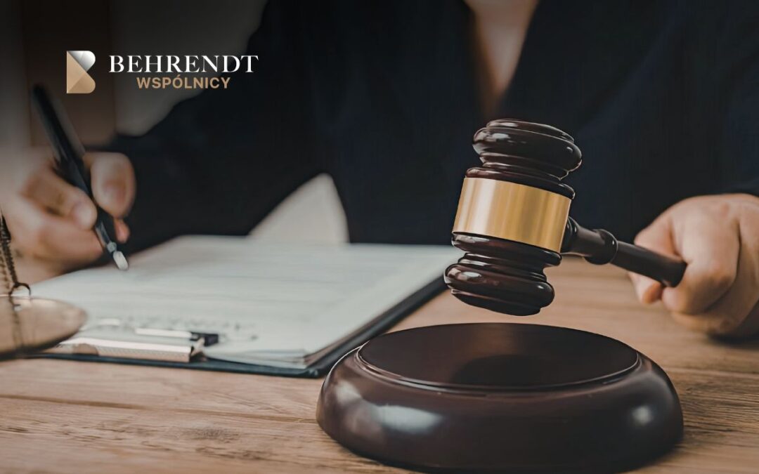 Gavel about to strike a desk with a contract and pen nearby; Behrendt Wspólnicy logo top-left.