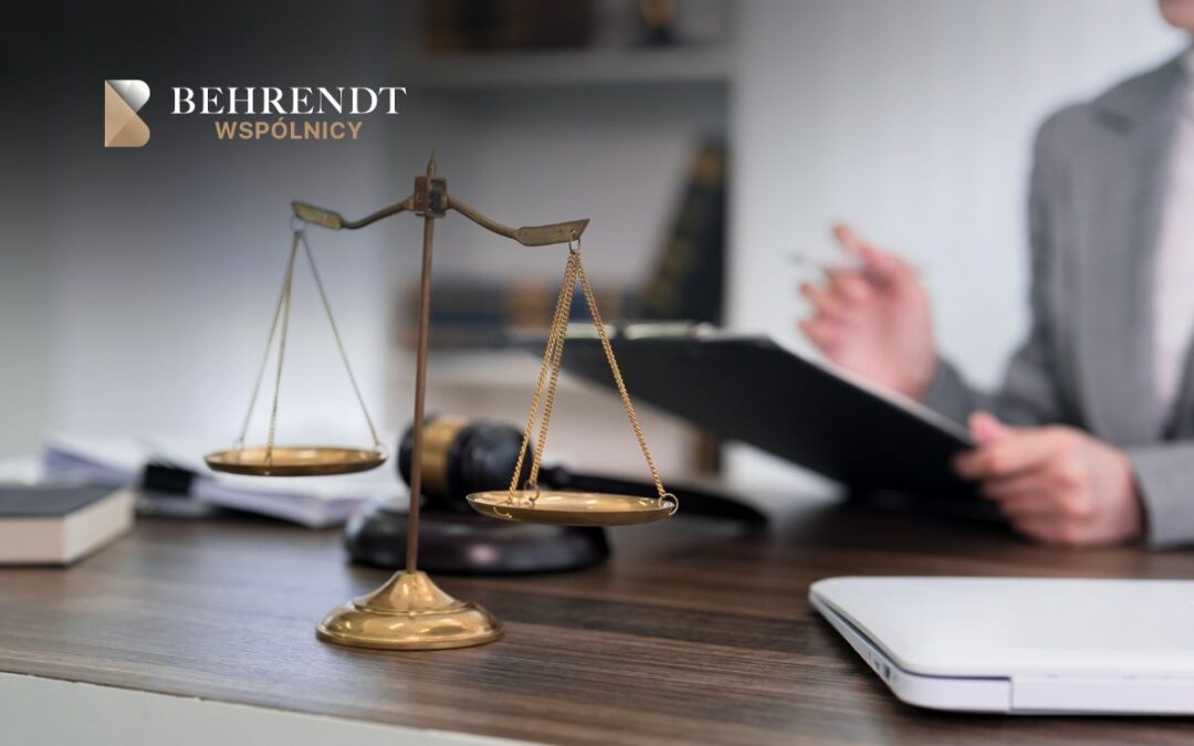 Scales of justice on a wooden desk with a blurred lawyer in a suit and a firm logo in the corner, signaling legal services.