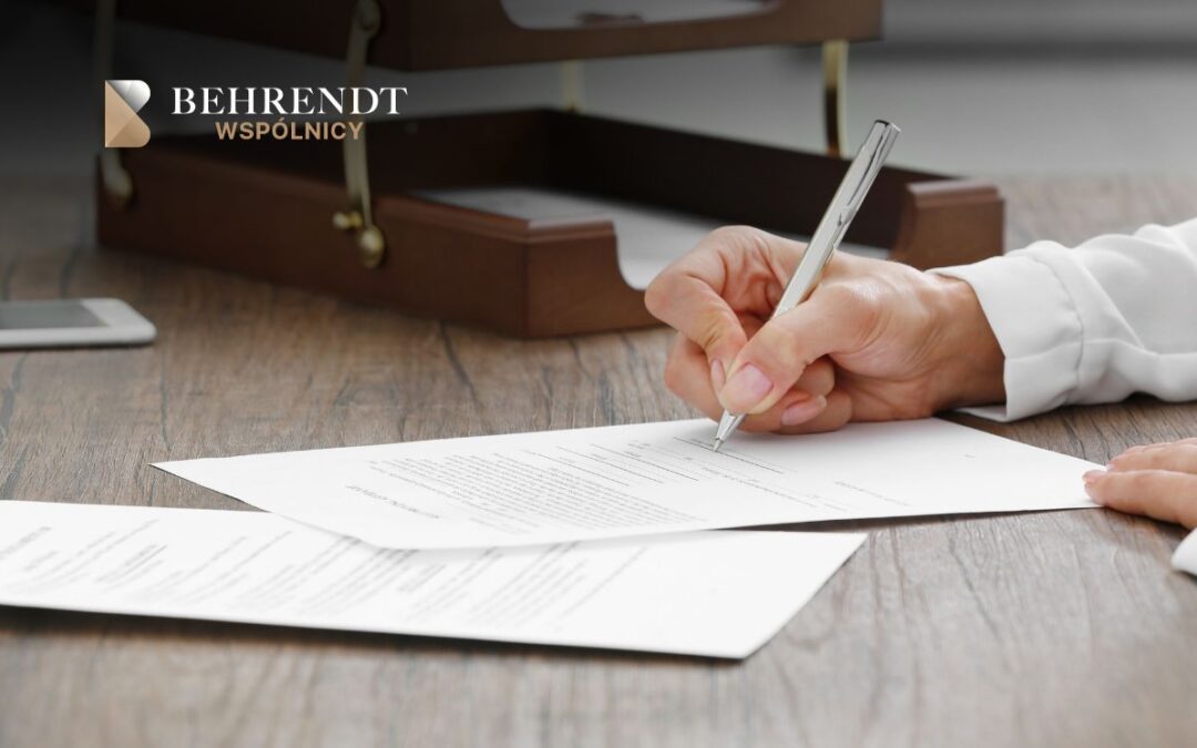 Hands signing a contract on a wooden desk with a pen; a briefcase and phone visible nearby and a Behrendt WSPÓLNICY logo in the corner.