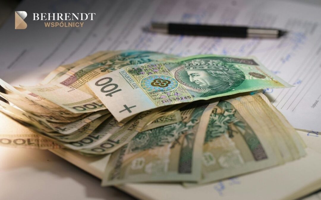 Zbliżenie na plik banknotów w pln. W tle widać czarny długopis i dokumenty