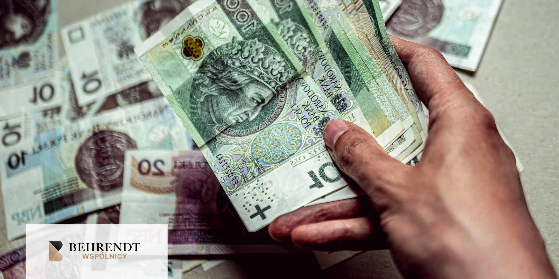 Zbliżenie na rękę uniesioną nad polskimi banknotami, podająca kilka banknotów stuzłotowych. 